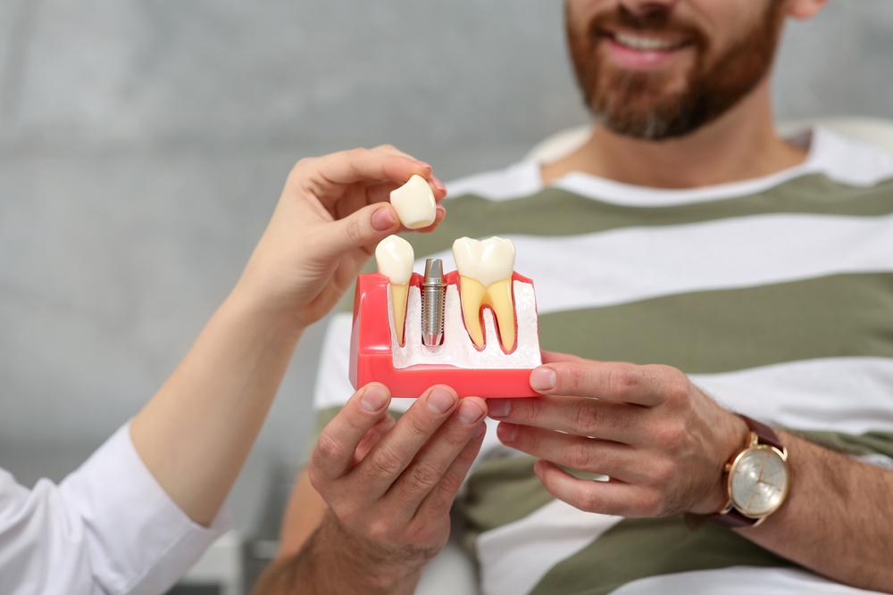 Understanding the Dental Implant Process – Dental Implants in Palm Desert A dentist explaining tooth replacement using a dental implant model, emphasizing precision, stability, and long-term solutions with dental implants in Palm Desert – Dental Implants in Palm Desert