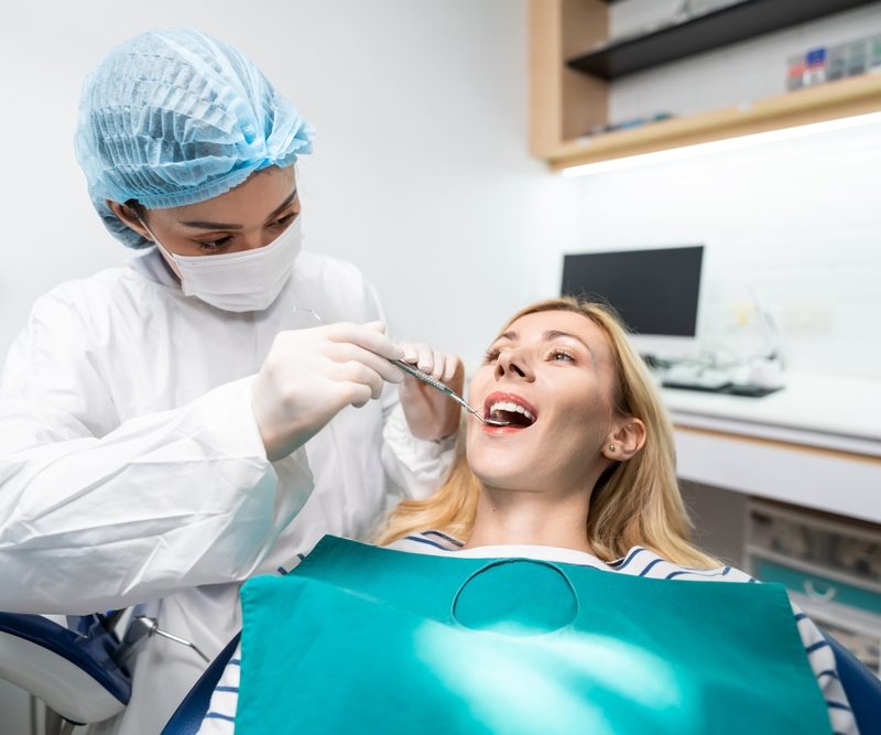 Female dentist examine tooth to Caucasian girl at dental health clinic. Attractive woman patient lying on dental chair get dental treatment from doctor during procedure appointment service in hospital