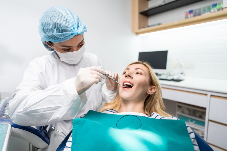 Female dentist examine tooth to Caucasian girl at dental health clinic. Attractive woman patient lying on dental chair get dental treatment from doctor during procedure appointment service in hospital