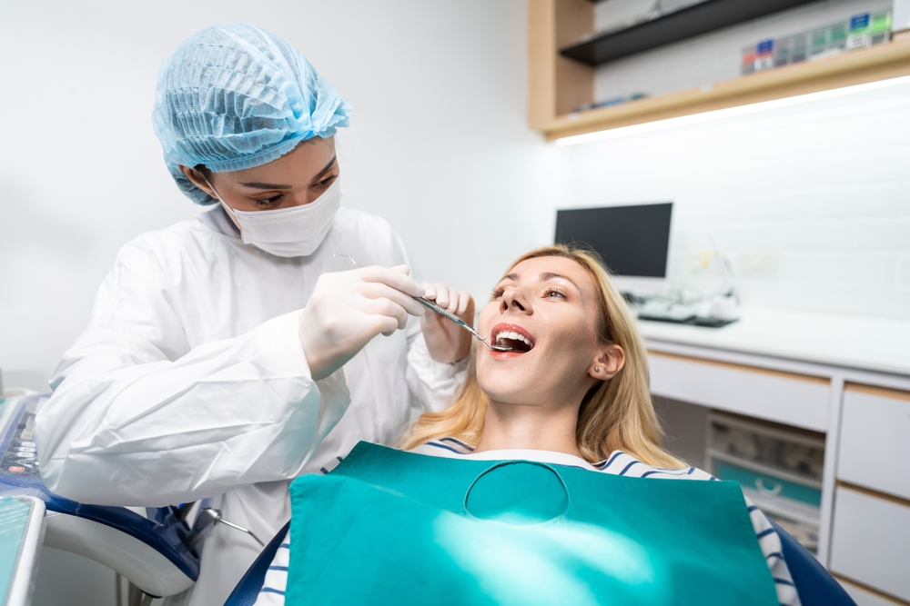 Female dentist examine tooth to Caucasian girl at dental health clinic. Attractive woman patient lying on dental chair get dental treatment from doctor during procedure appointment service in hospital