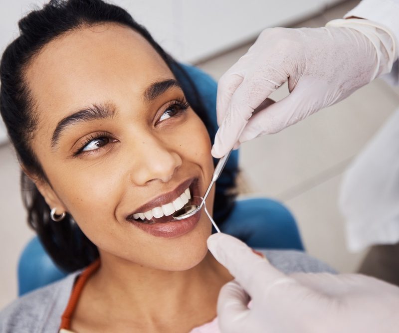 Hands, woman or dentist with tools for dental procedure, clean teeth or cavity removal in clinic. Mirror, excavator or patient with medical orthodontist for gum care, oral hygiene or smile for health