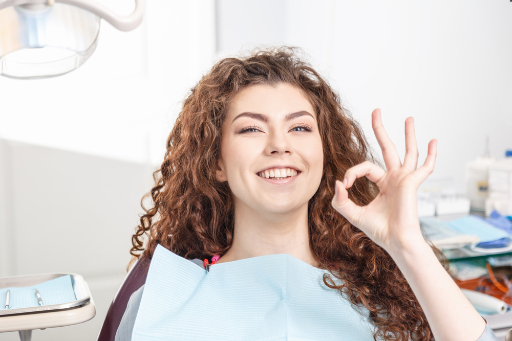 A smiling patient seated in a dental chair giving an “OK” gesture, representing comfort, confidence, and positive experiences with sedation dentistry – Sedation Dentistry