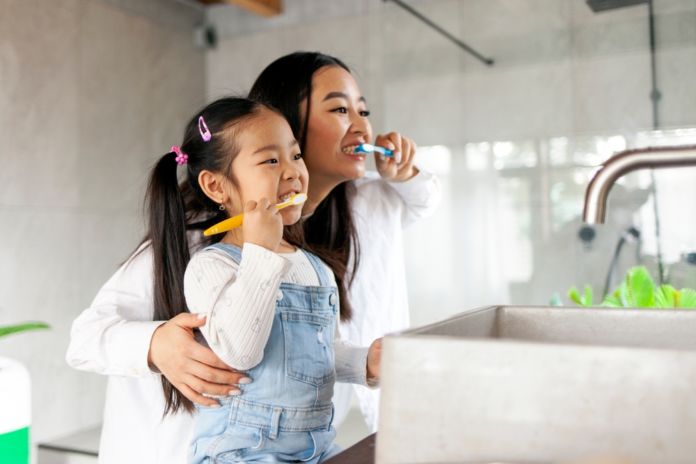 Teaching Healthy Oral Habits at a Young Age – Pediatric A parent and child brushing their teeth together at the sink, reinforcing daily oral hygiene routines supported by pediatric dentistry – Pediatric