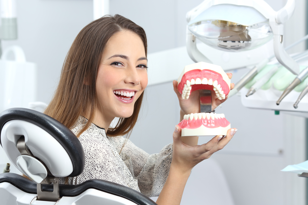 Understanding Dental Anatomy and Treatment Options – Restorative Dentistry A smiling patient holding a dental model to better understand tooth structure and treatment options offered through restorative dentistry – Restorative Dentistry