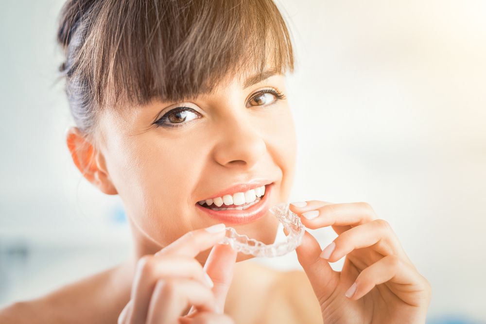 Patient Holding Invisalign Clear Aligners – Invisalign in Palm Desert A smiling patient holding Invisalign clear aligners, highlighting comfortable, removable orthodontic treatment for straighter teeth – Invisalign in Palm Desert