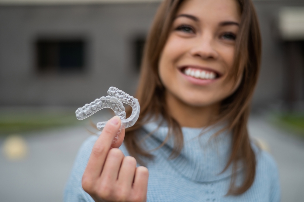A smiling patient holding Invisalign aligners, showcasing modern orthodontic care designed for convenience, comfort, and confidence – Invisalign in Rancho Mirage